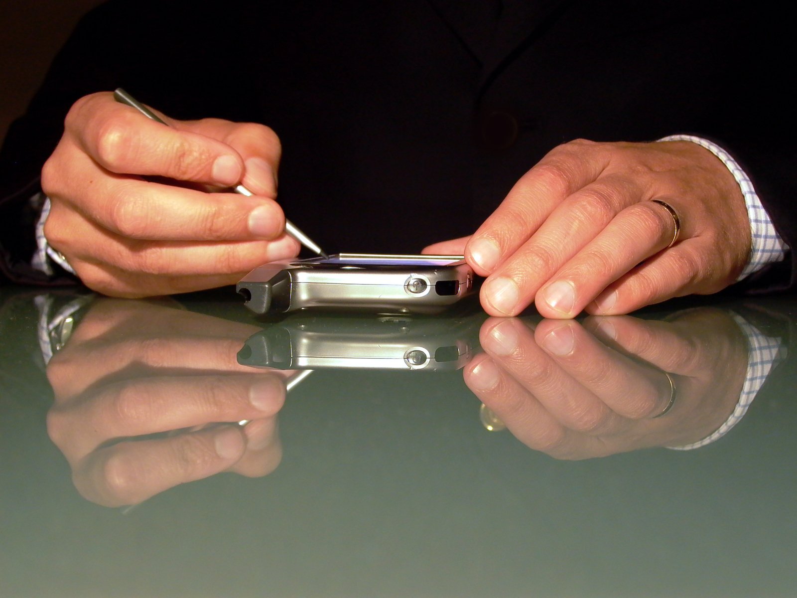 two hands hold a cell phone on top of a table