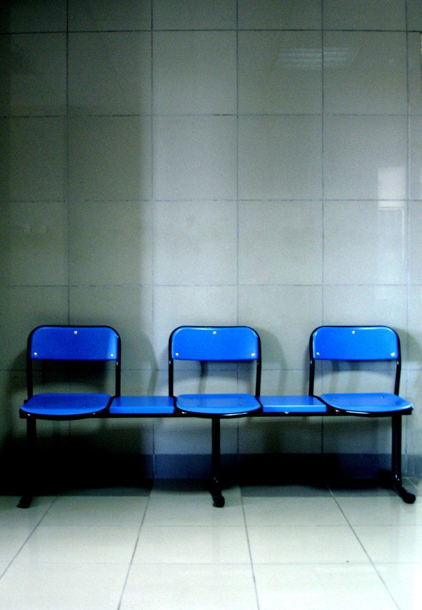 three blue benches sitting in front of a wall