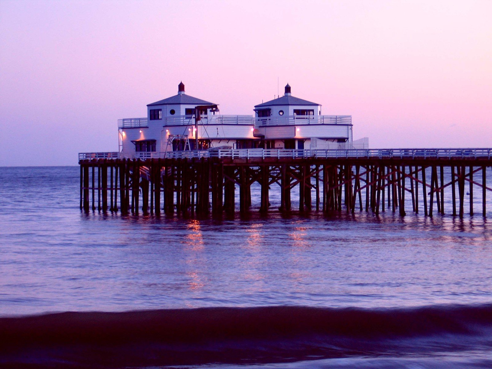 there are three buildings on the pier by the ocean