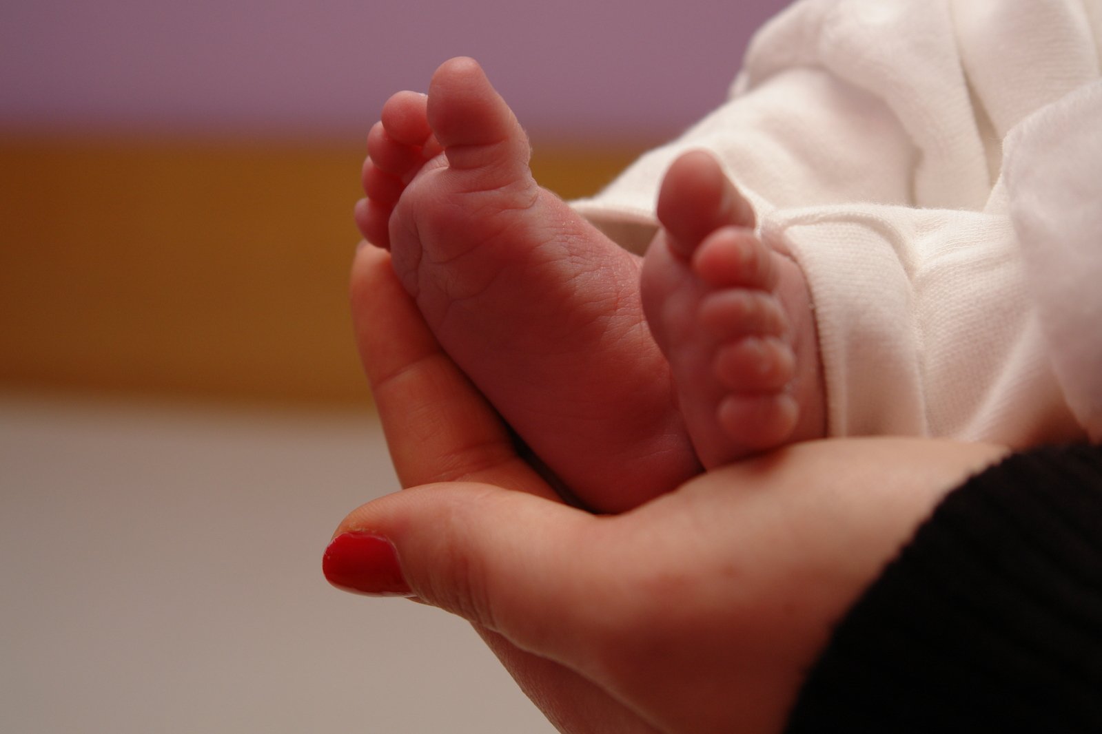 small baby feet being held by someone in a room