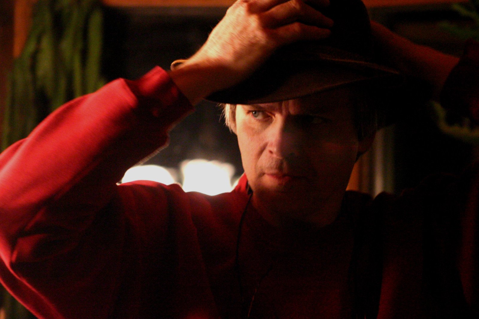 a man is covering his hat with a red jacket