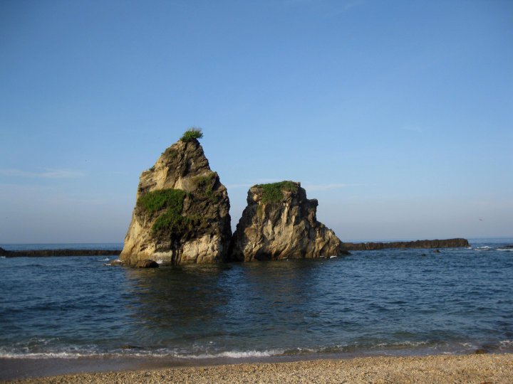 a large rock sitting on top of a beach next to the ocean