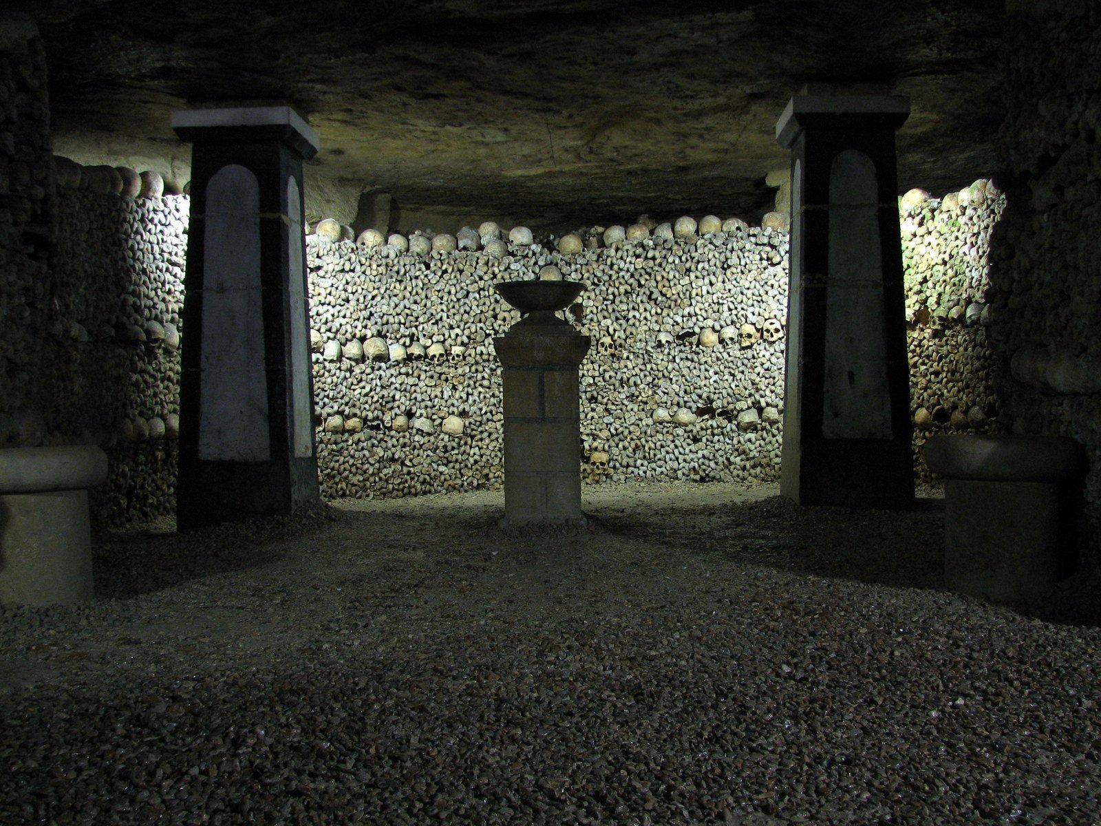 a white vase in an old stone building with skulls on the walls