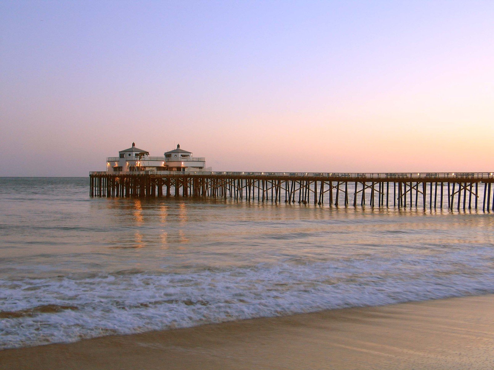 a pier at the beach with waves crashing against it