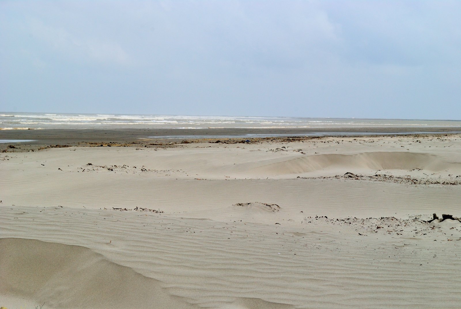 the beach is covered with sand, water and clouds