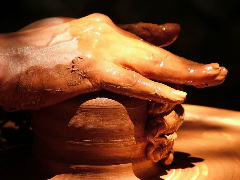 a potters hands on top of a pottery pot