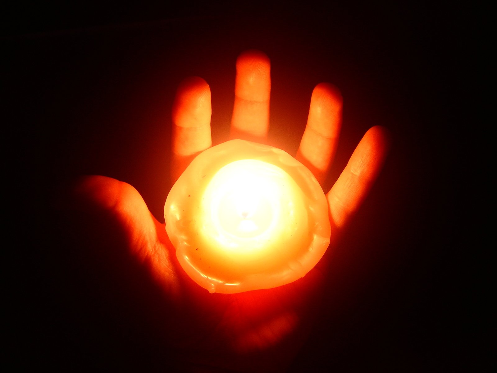 a person holds up a glowing hand in the dark
