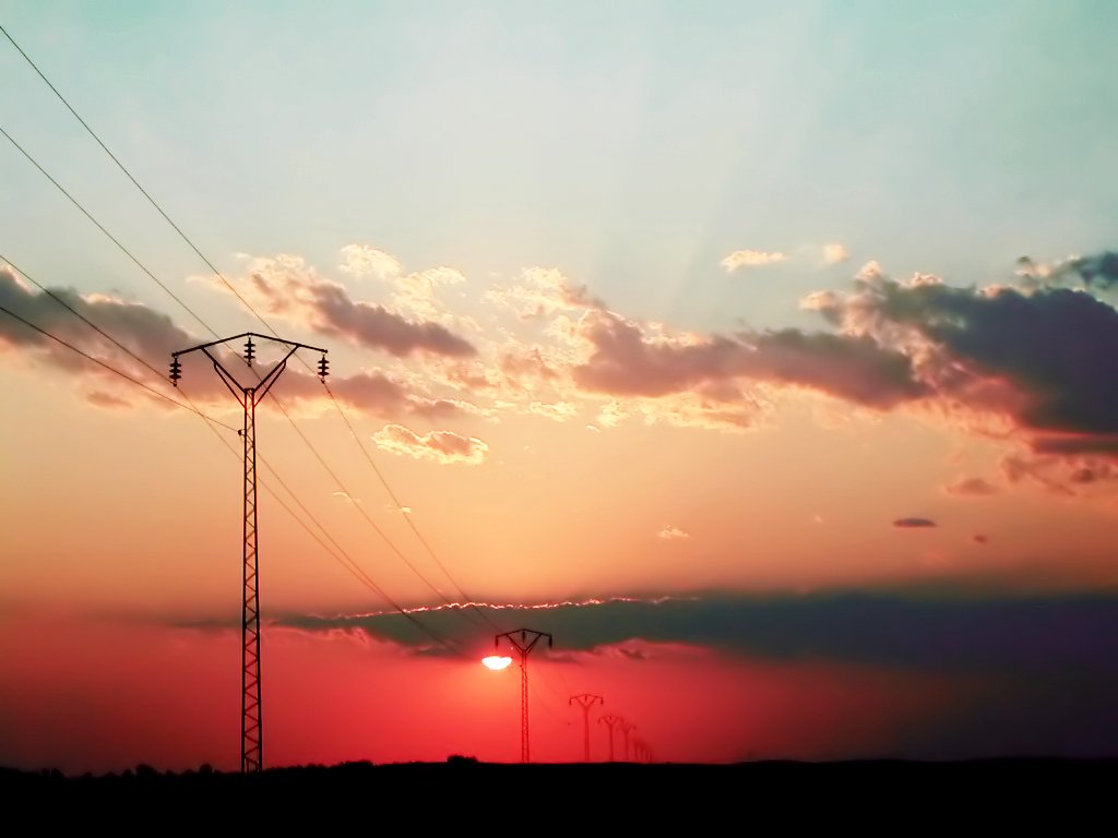 the sun shining through some clouds above power lines