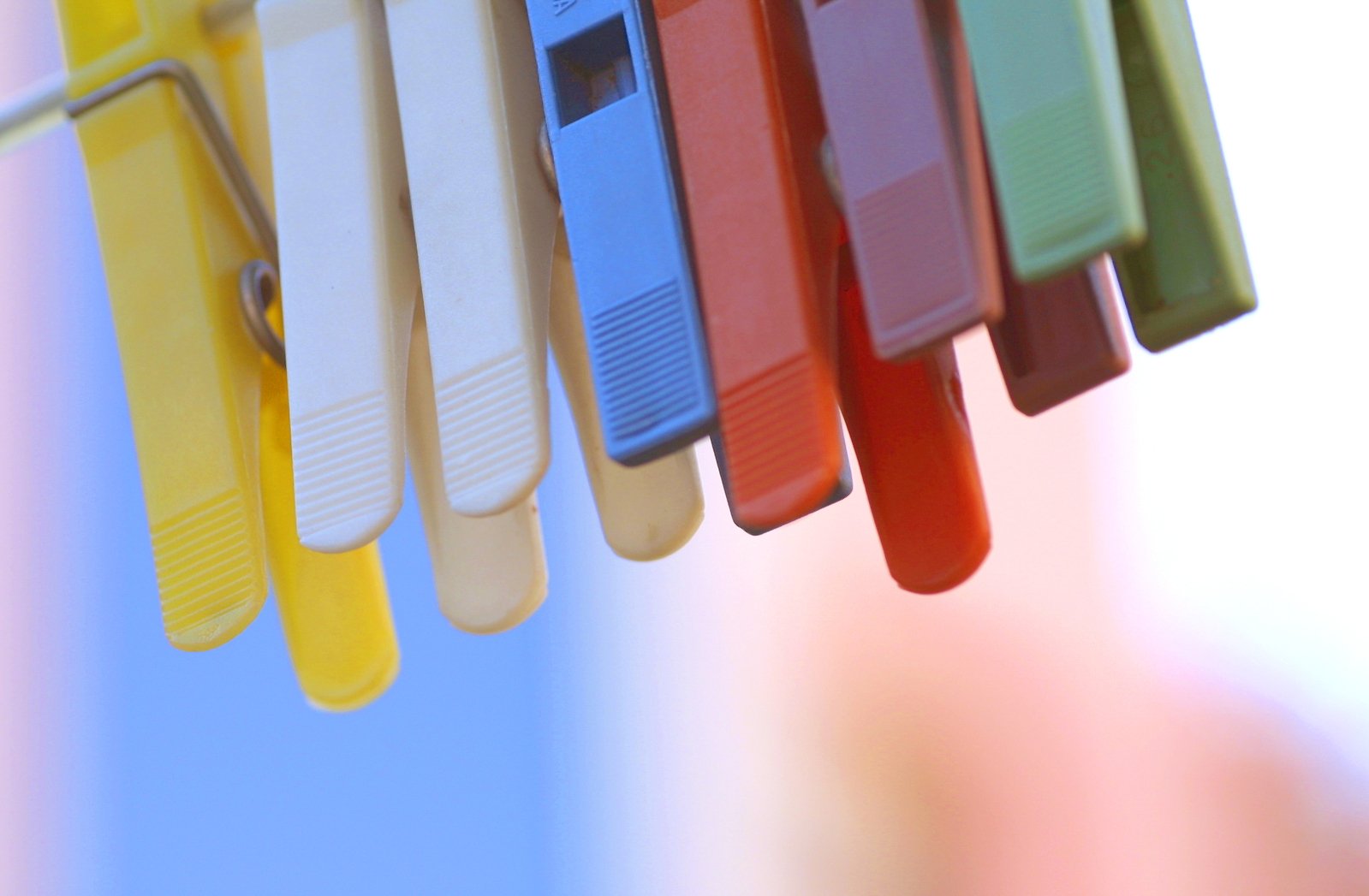 small rainbow colored plastic pegs hanging on white line