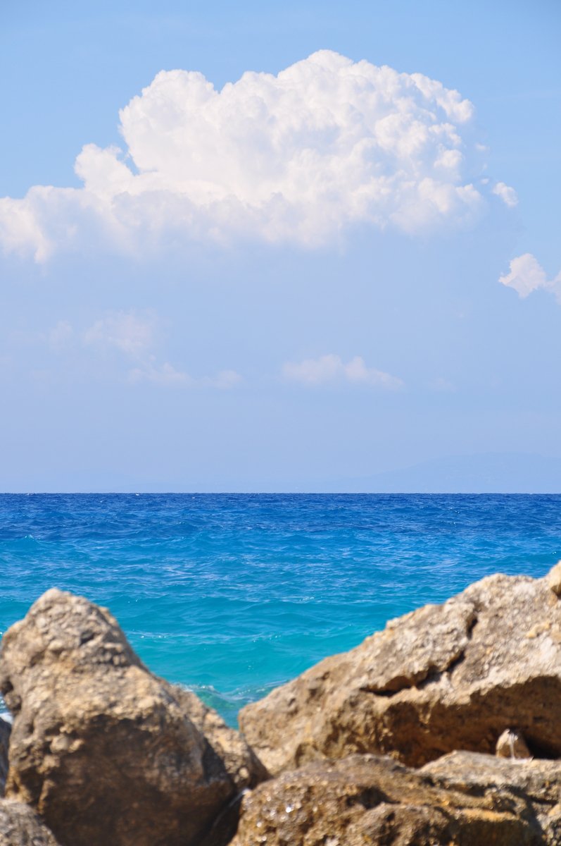 rocks in front of a body of water under a cloudy sky