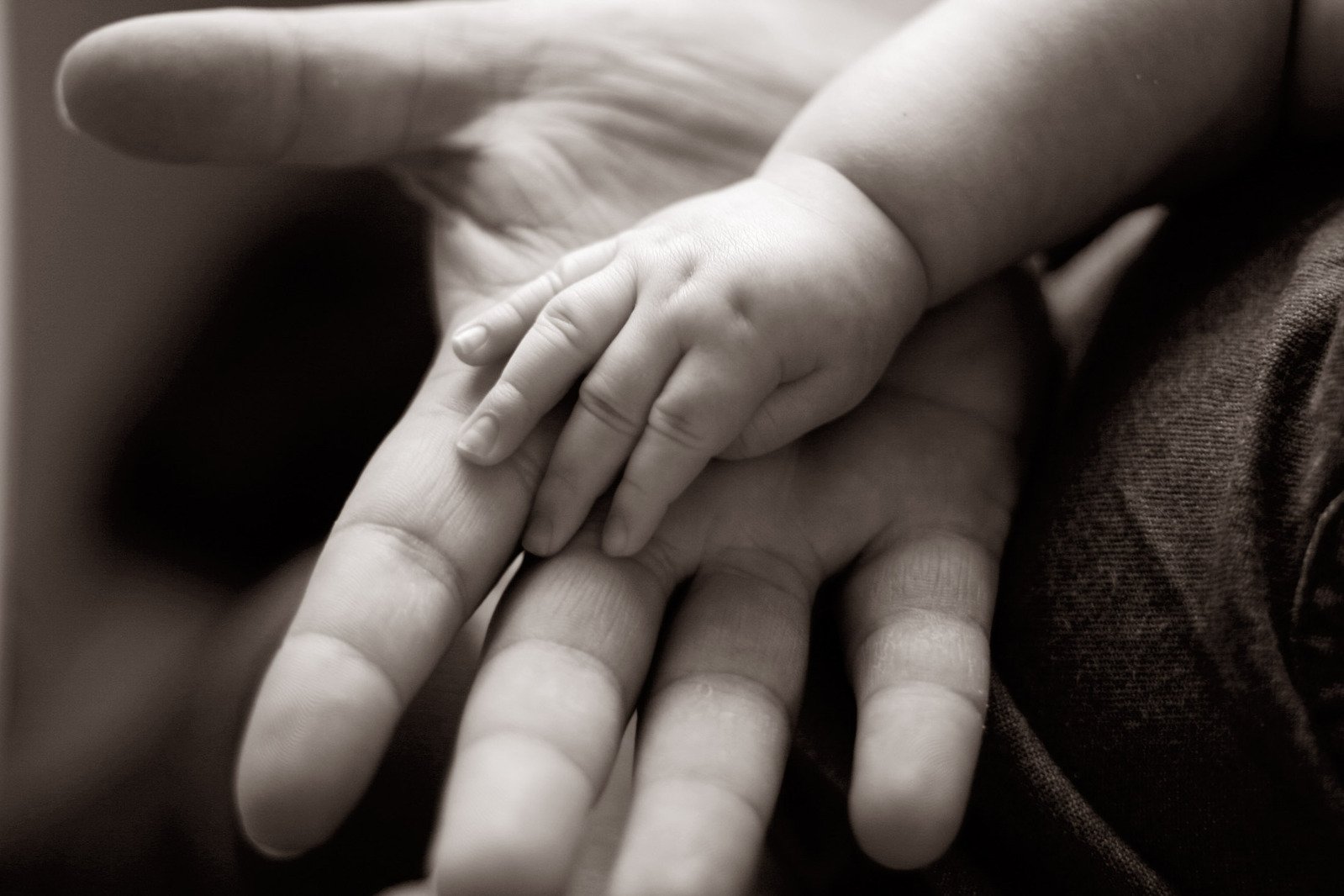 a black and white po of a man holding the hands of a baby