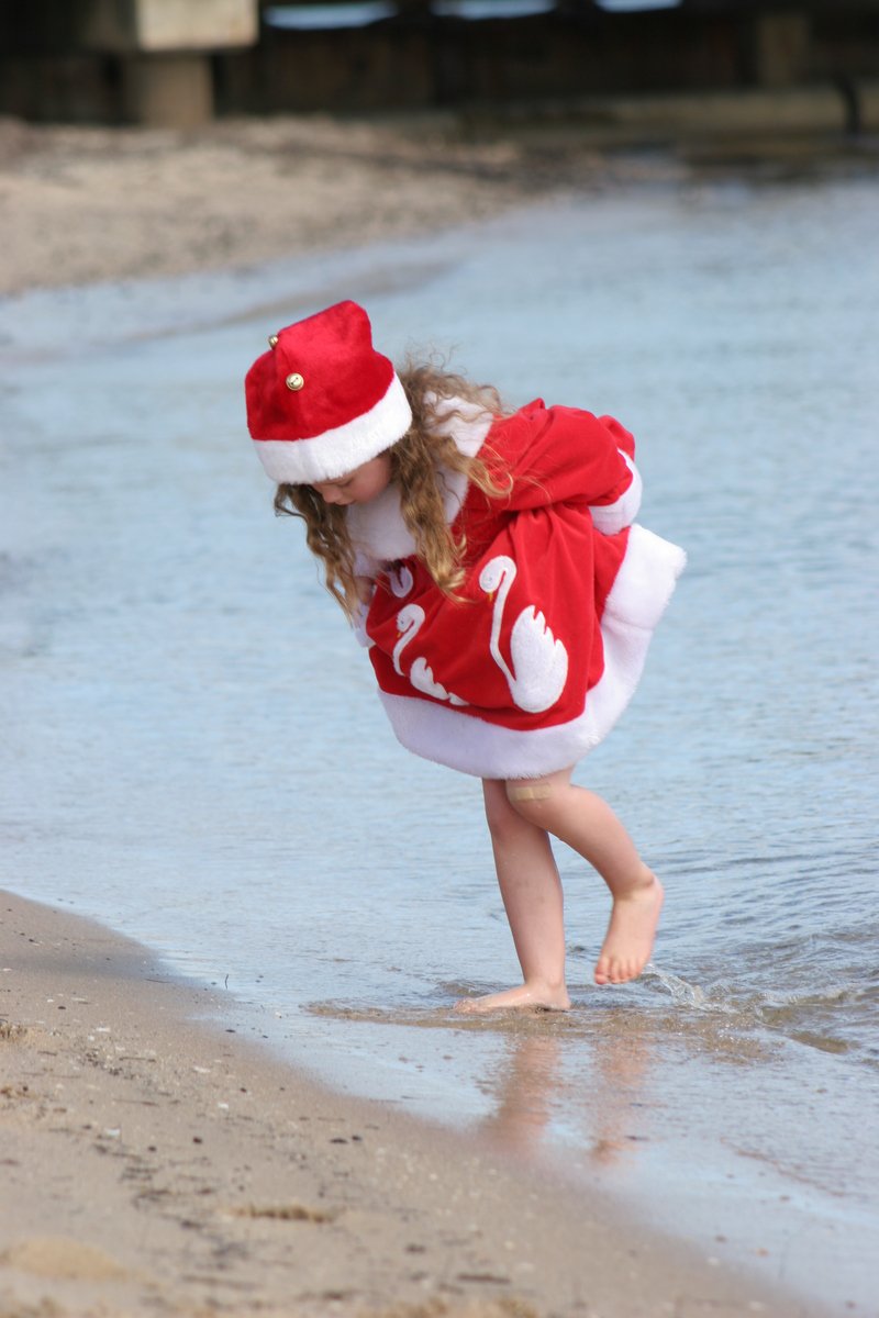 a little girl in santa hat playing on beach