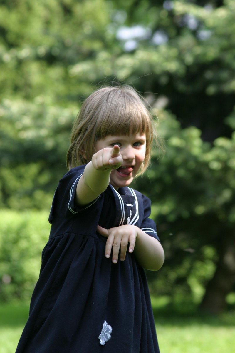 a little girl in a dress pointing her finger
