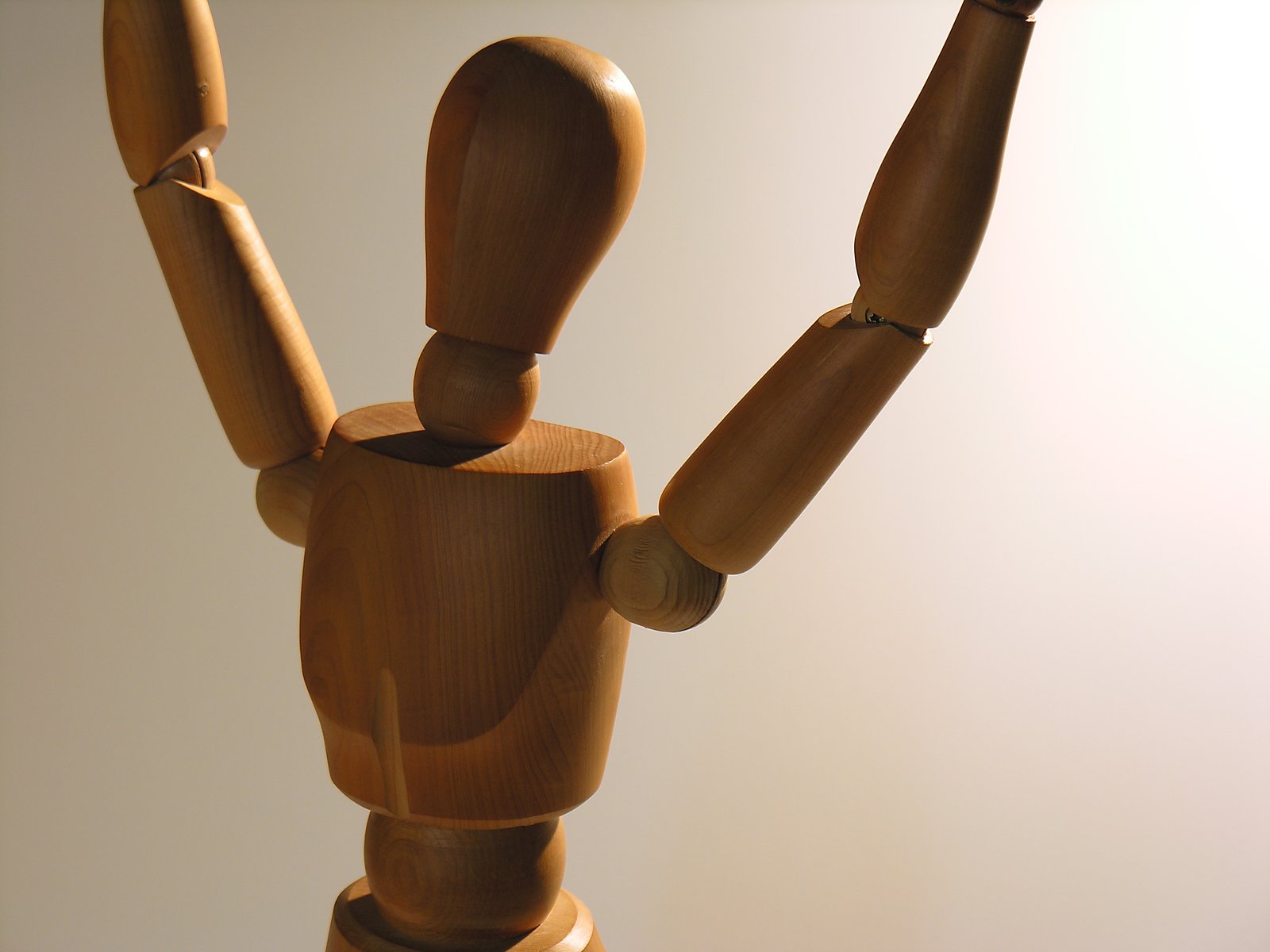a wooden sculpture of a person with two hands up in the air