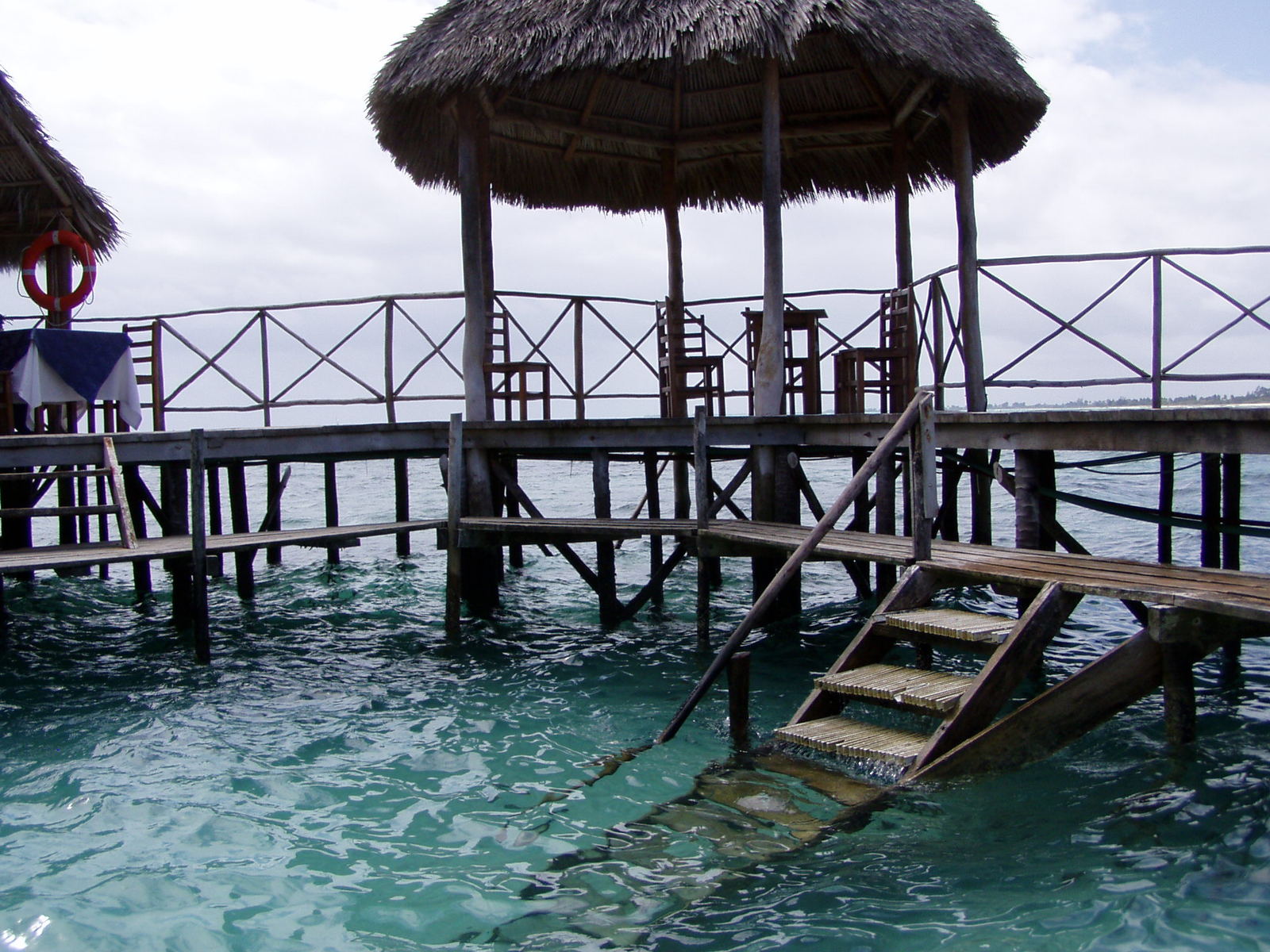 wooden dock with stairs and thatch huts on the water