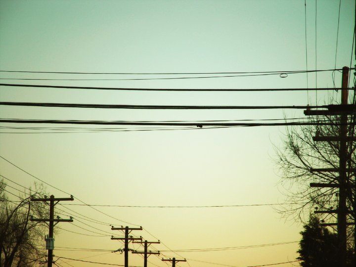the sun is setting over electrical power poles