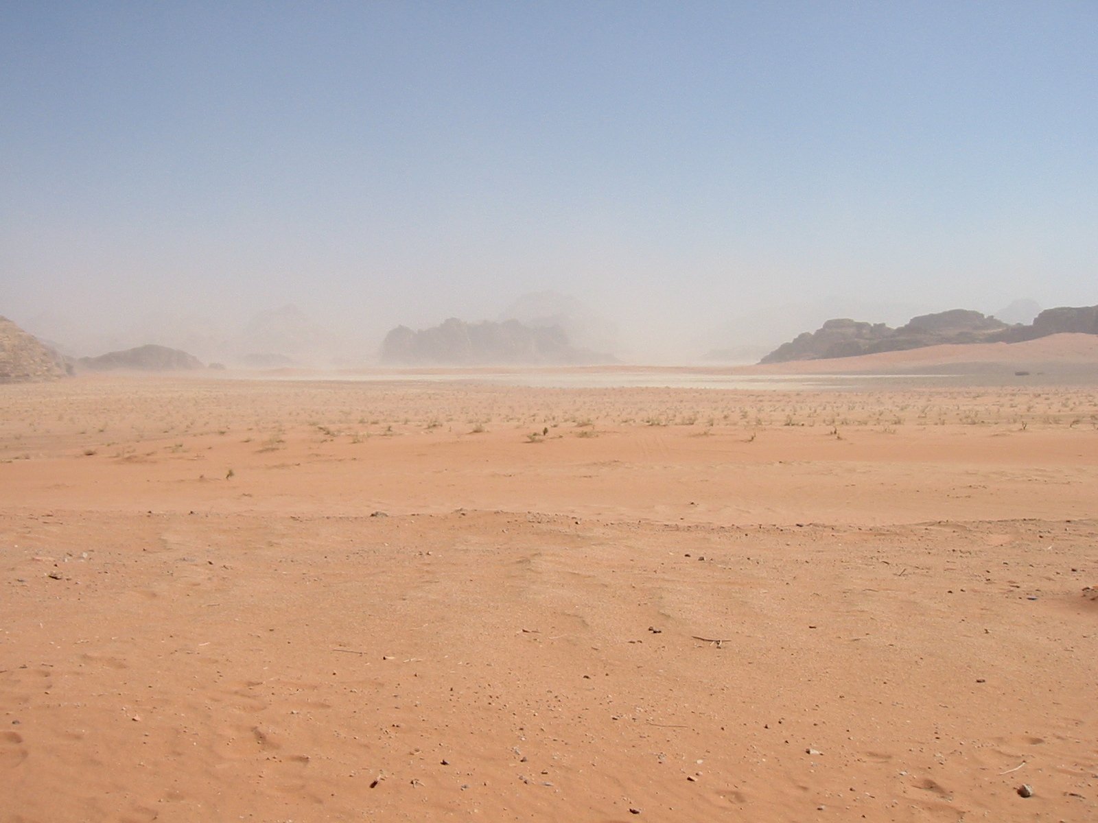 two people in the desert riding horses on the sand