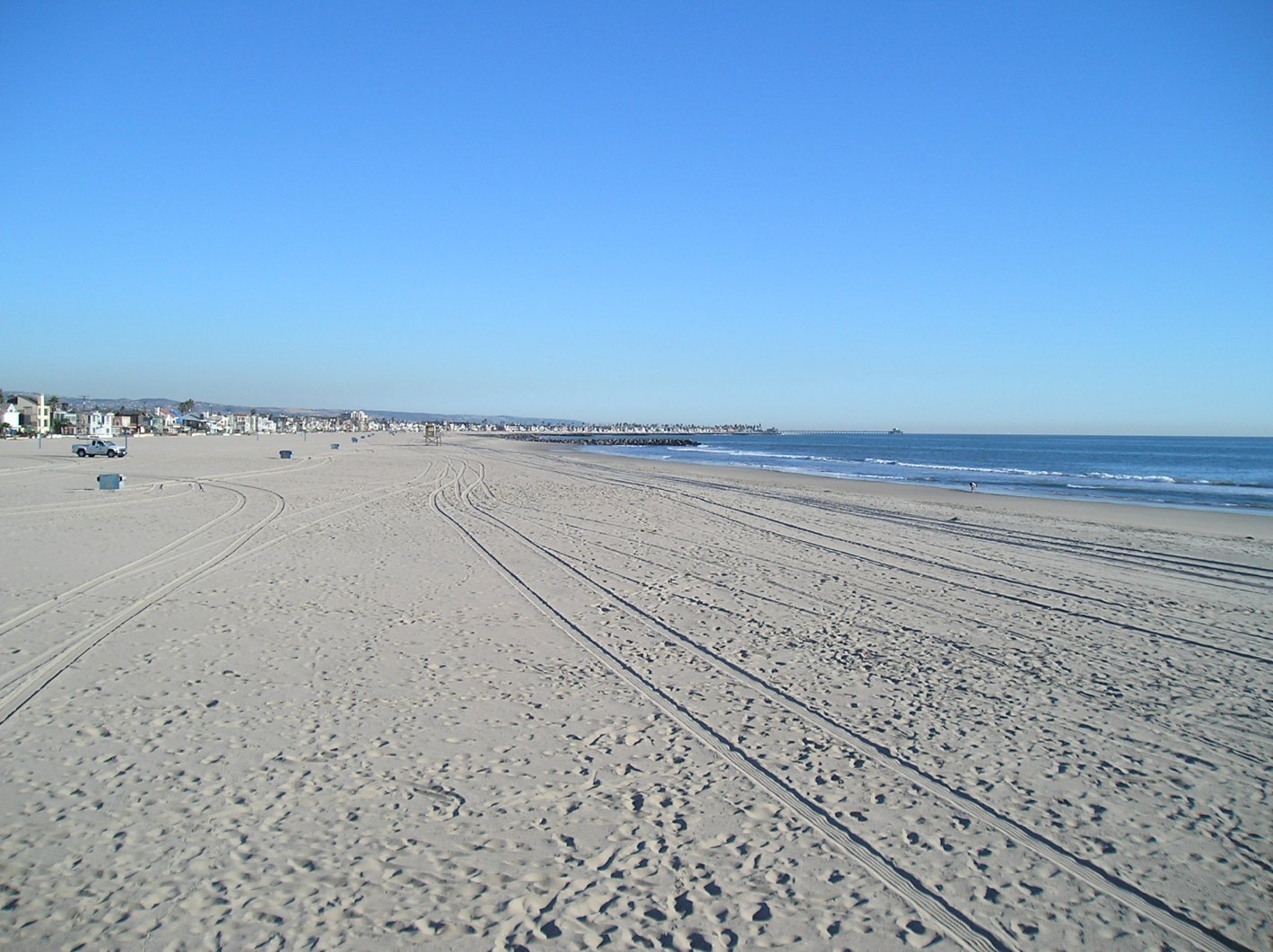 a beach with a line of white sand and buildings