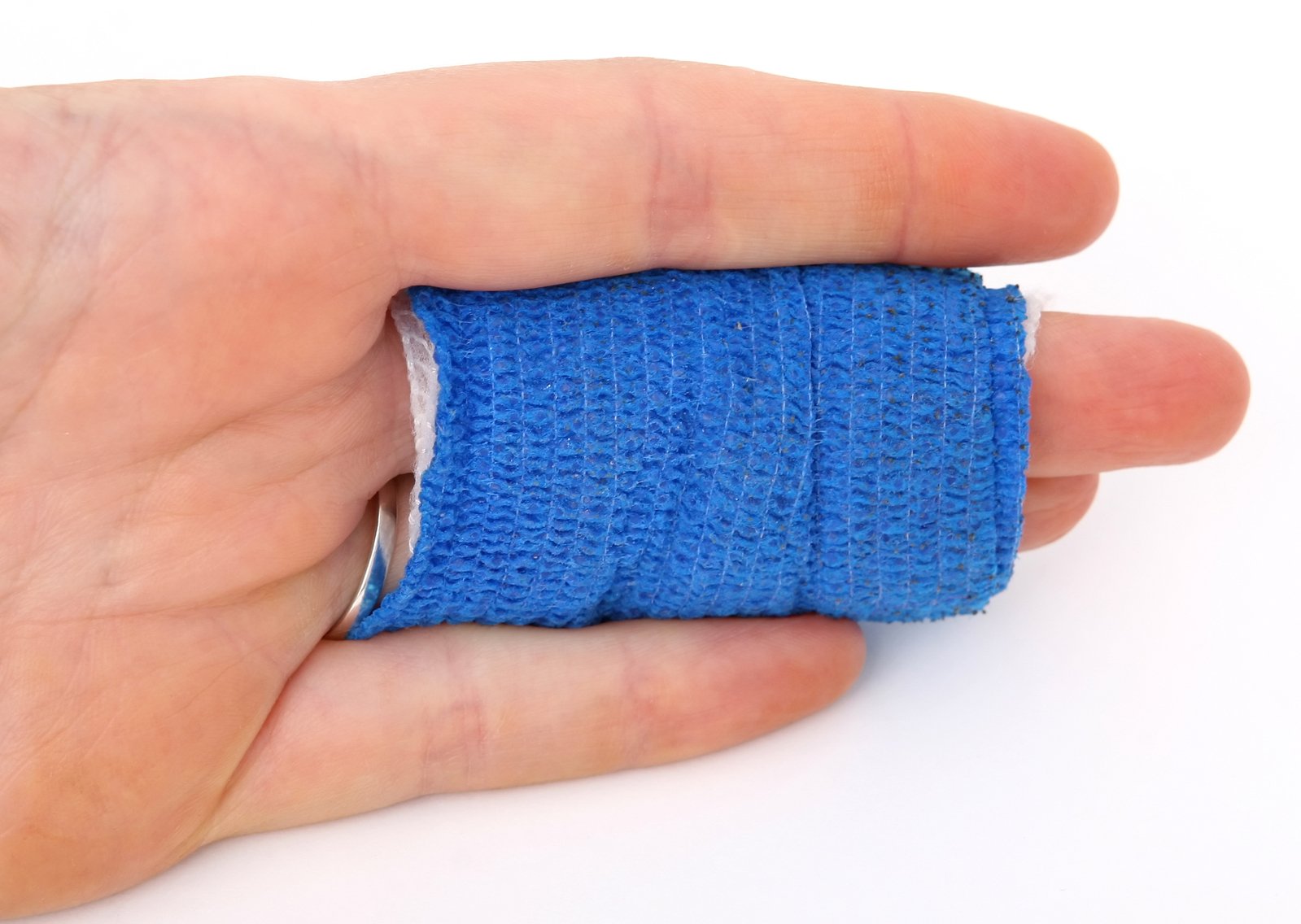 a hand holds a blue bandages in front of a white background