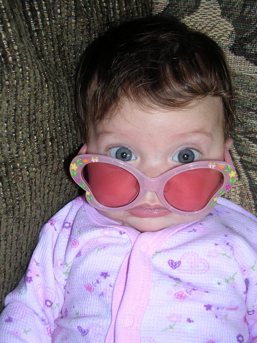 a baby wearing glasses with large pink cheeks on a chair