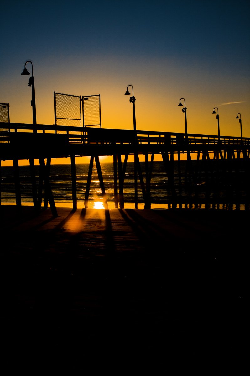 a pier with light poles and street lights against a blue sky