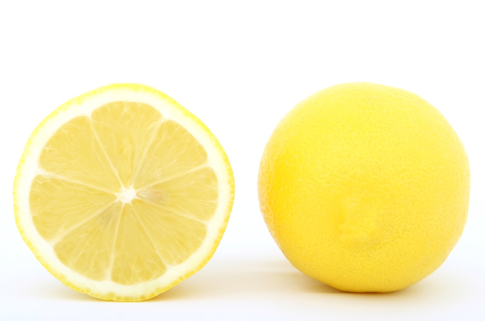 a half sliced lemon sits next to an orange