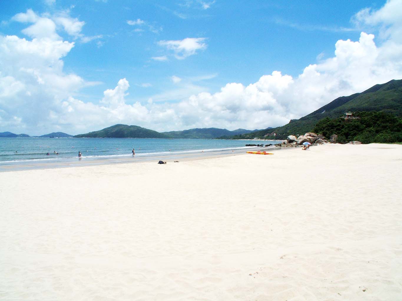 people walking along the beach on the sand