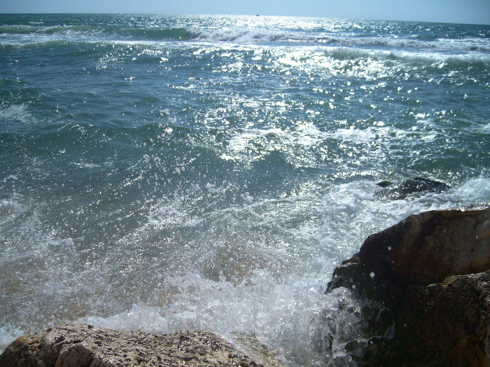 some rocks are next to the shore and some water