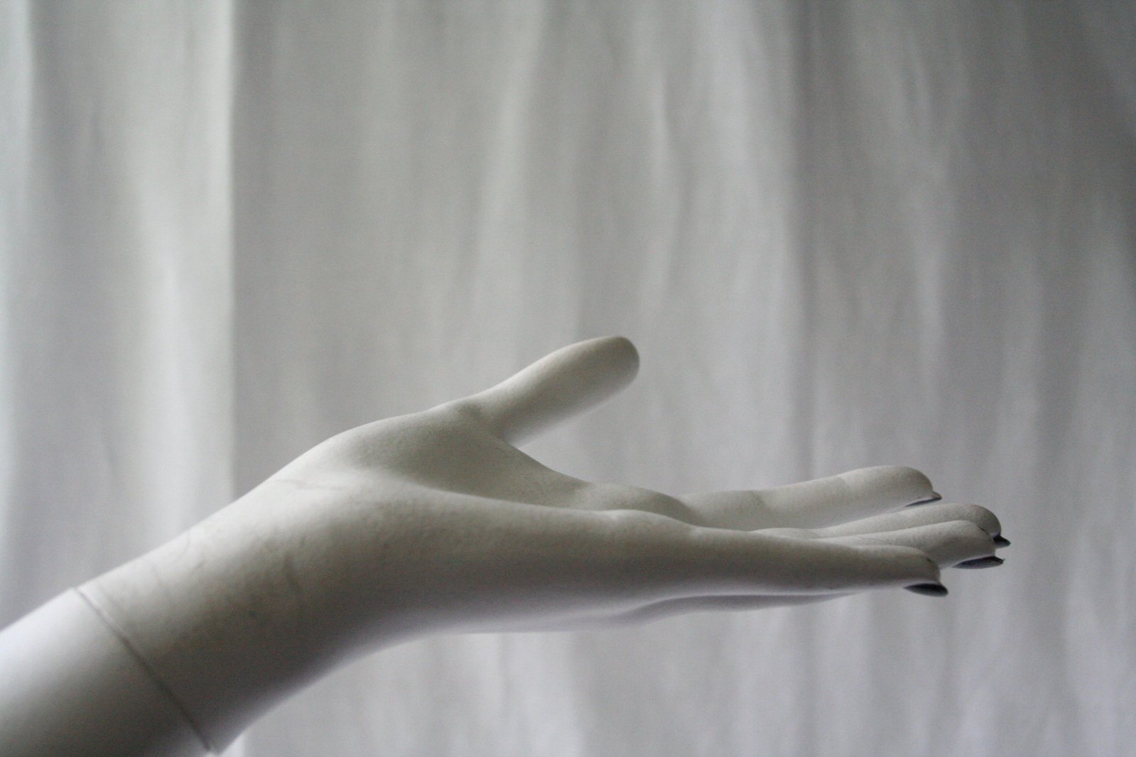 a white hand is reaching towards a curtain
