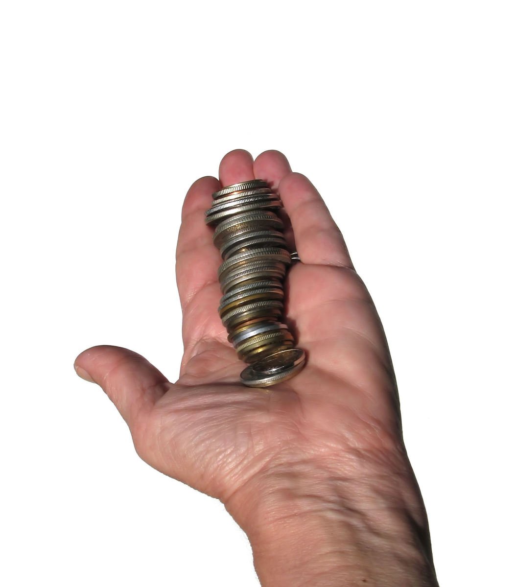 a person's hand holding up a pile of coins