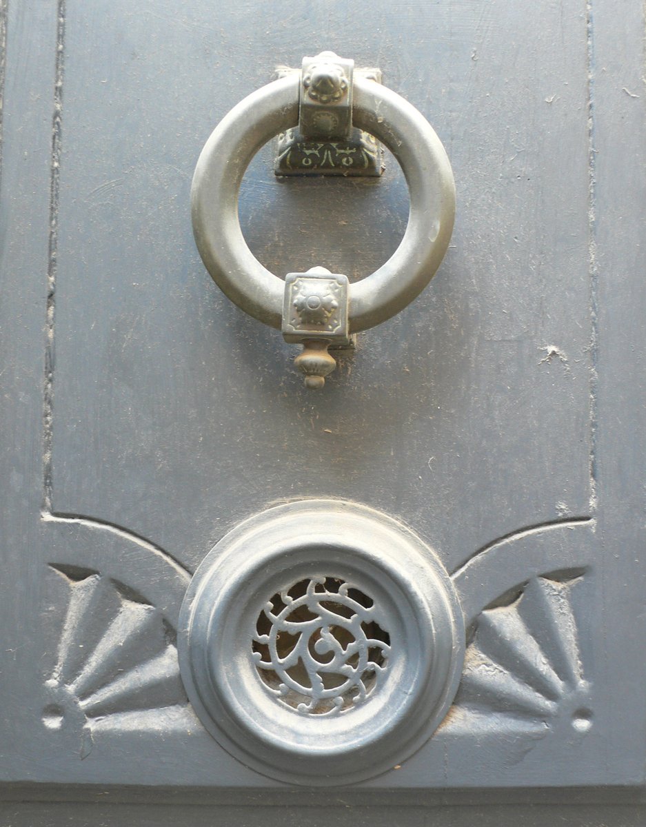 the handle on a metal door with a metal circular and oval design on it