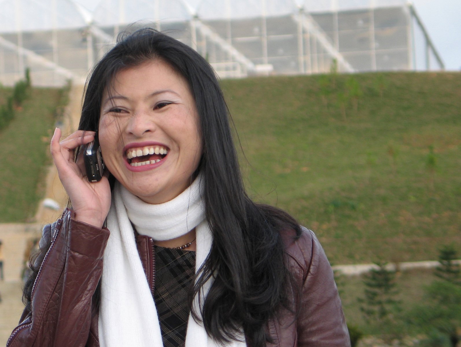 woman laughing while on cellphone near a field