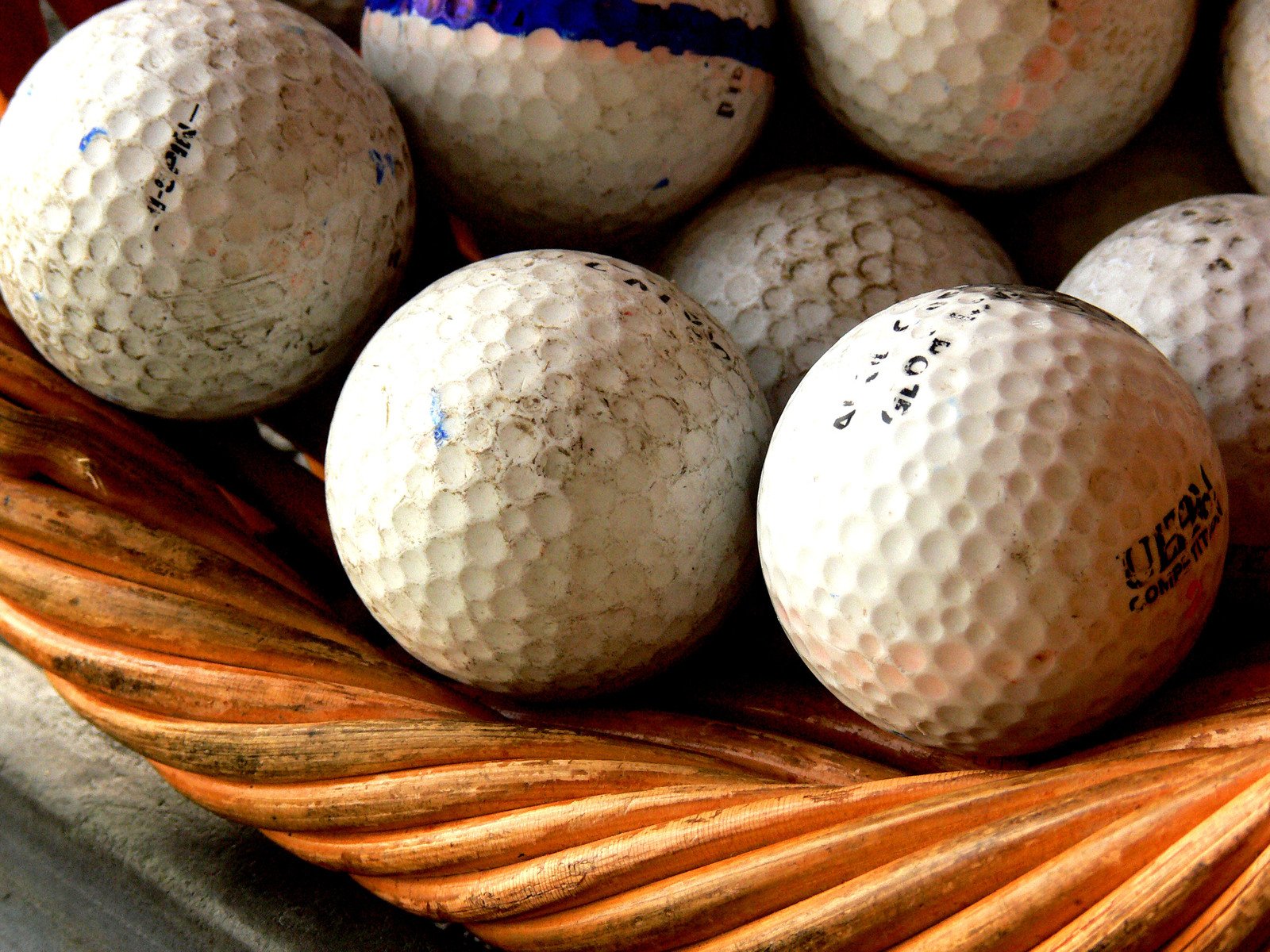 a basket full of golf balls, including one of them has handwriting