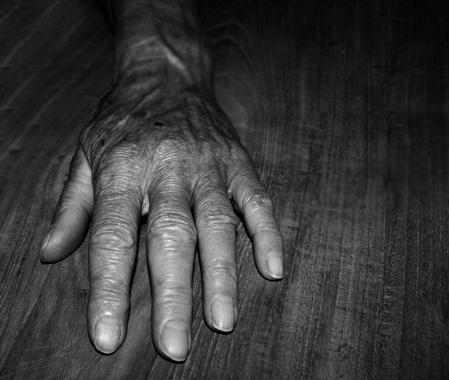 an old person's left hand on a wooden floor