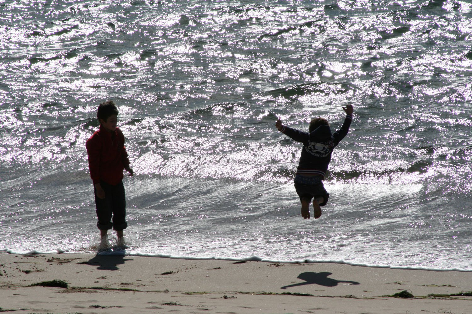 two people jumping into the air with waves crashing over them