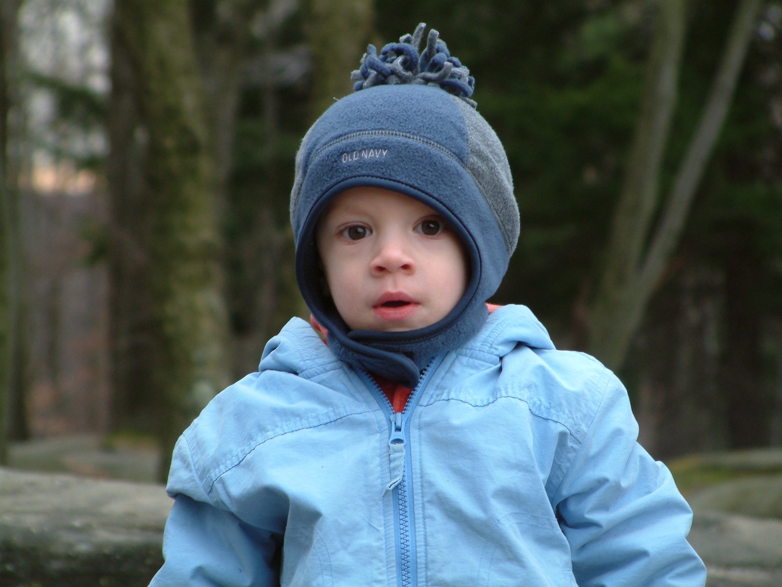  wearing blue jacket and hat with trees in background