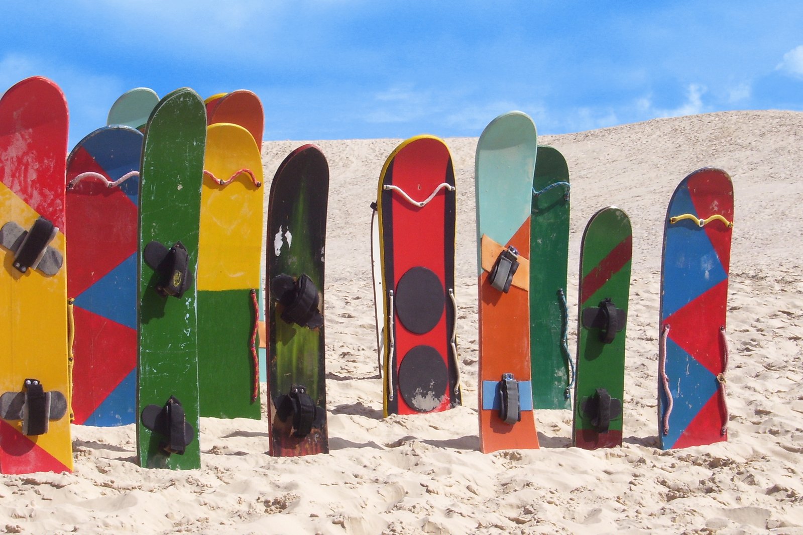 multi colored skis stuck in sand with sky background