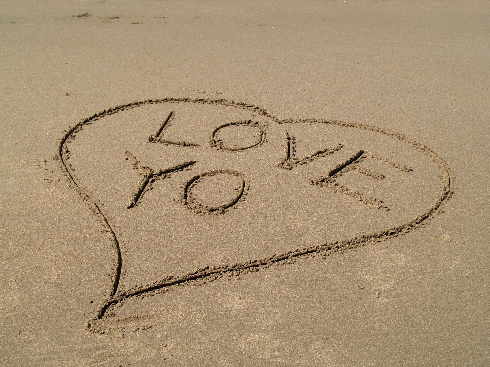 a heart drawn in the sand with the word love you written in it