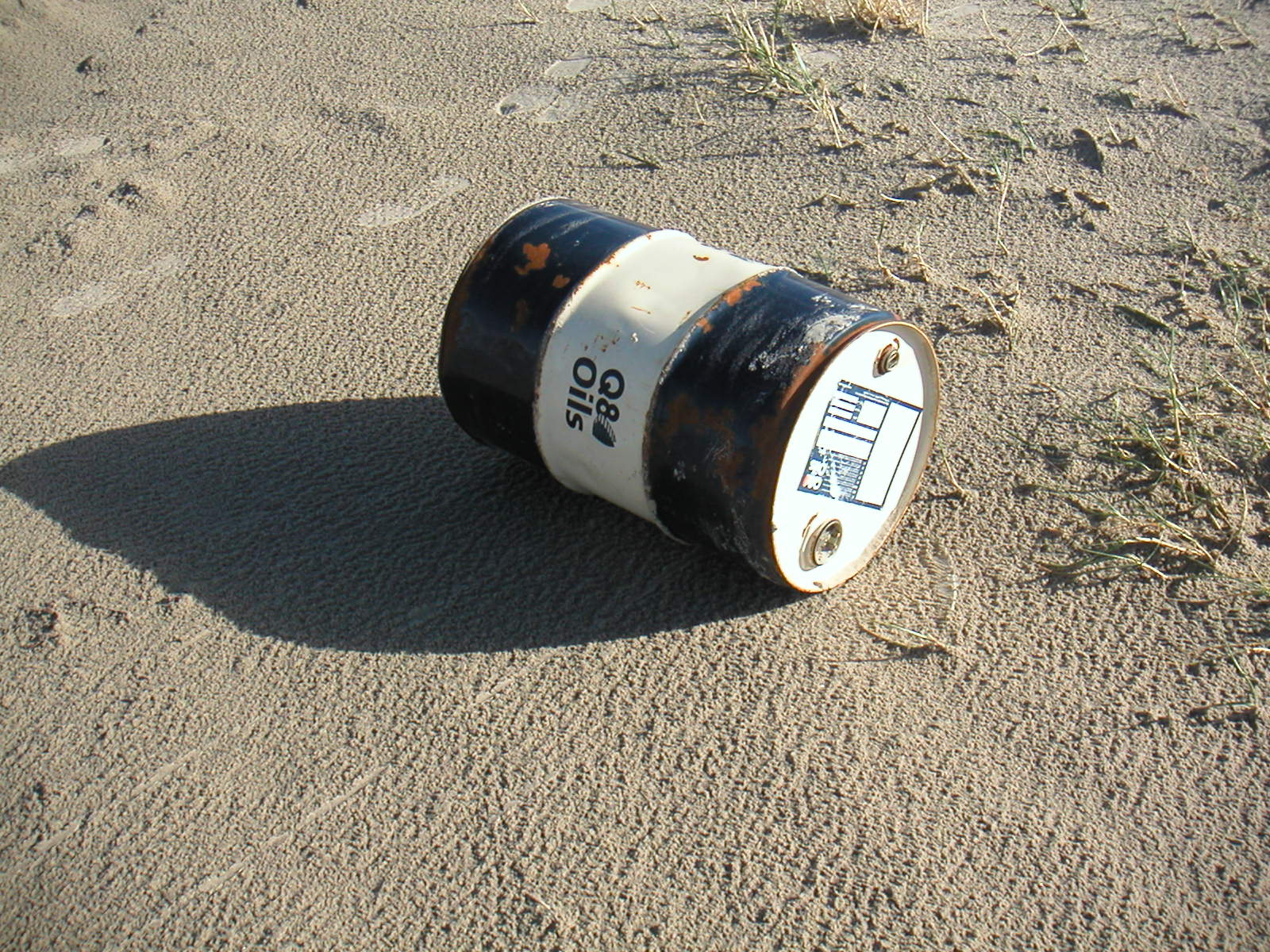 a trash can left in the sand with the side light on