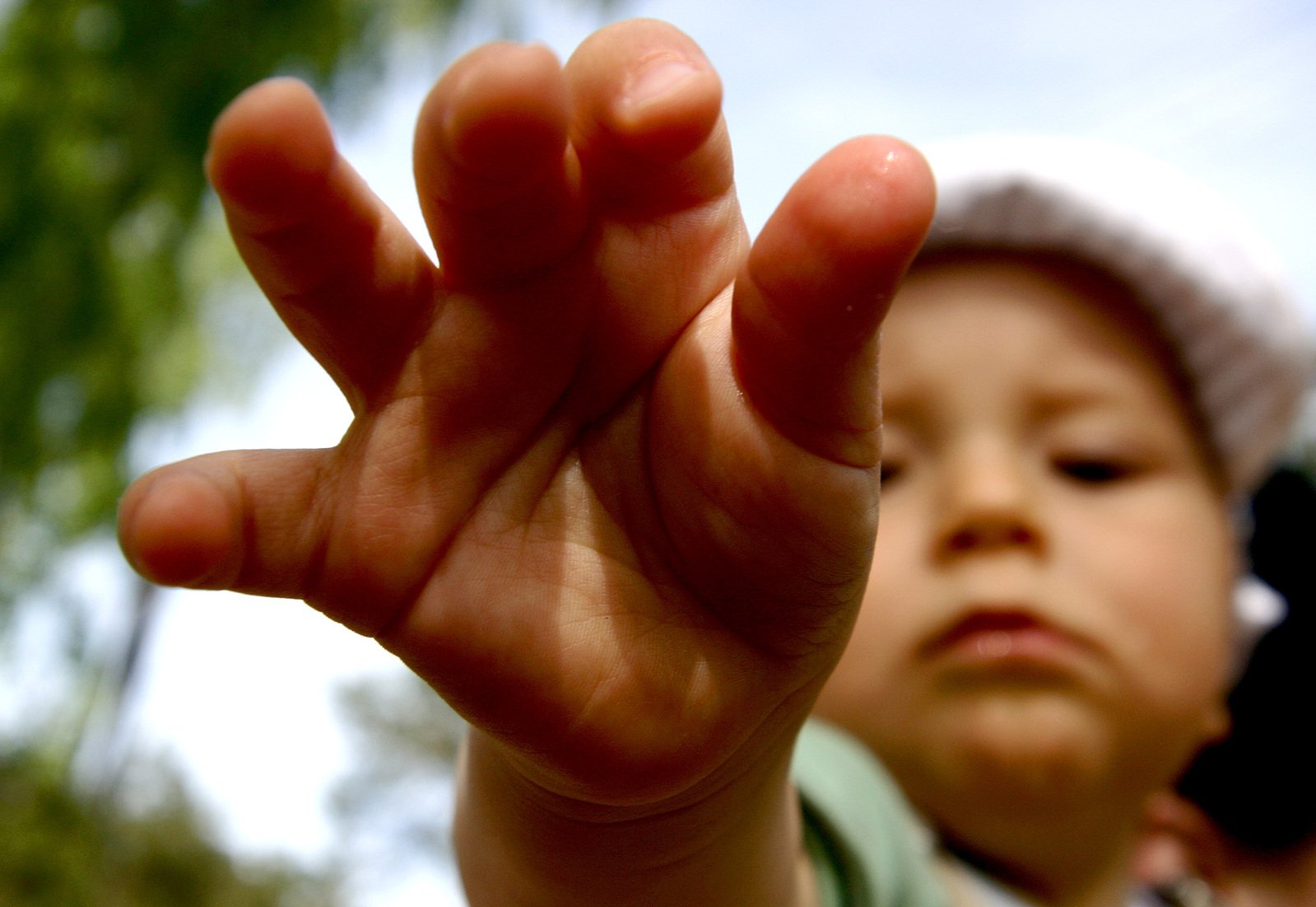 a boy holds his fingers up so he can see the sky