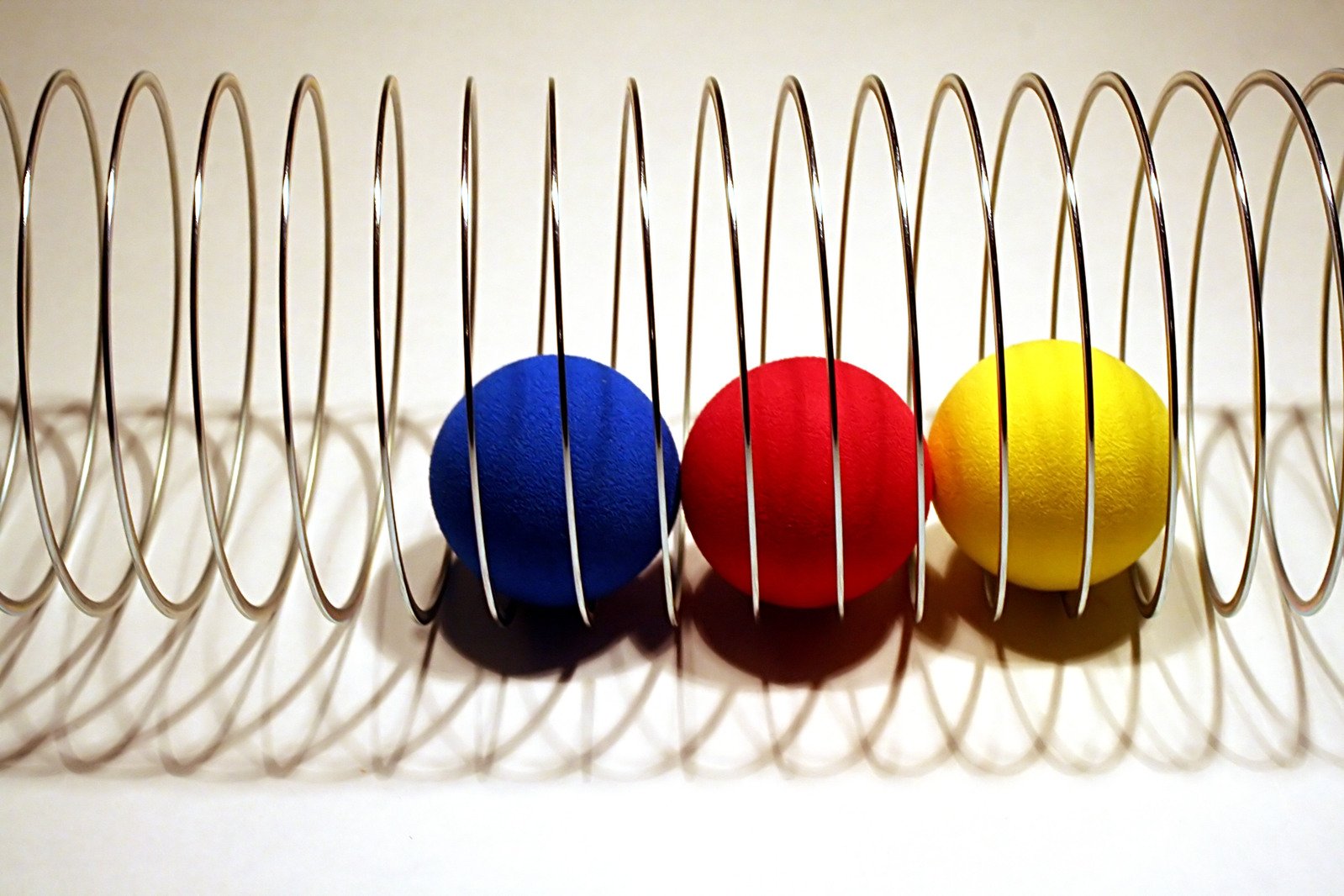 an odd arrangement of four colorful balls in front of metal wire sculptures