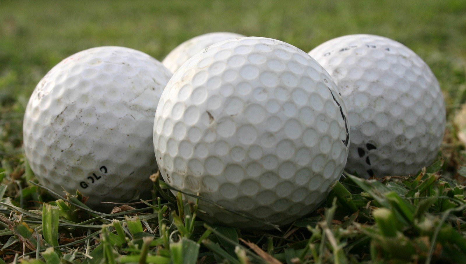 three white golf balls that are laying on the ground