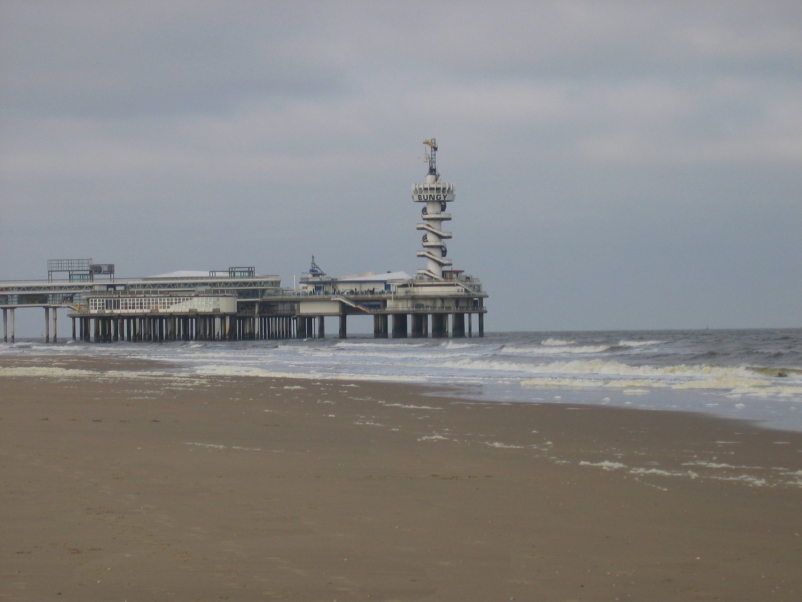 a pier with a clock tower in the background and water waves