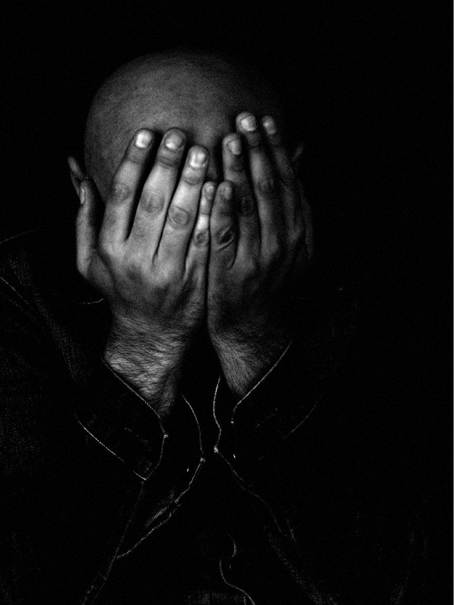 a man covering his face with his hands in black and white