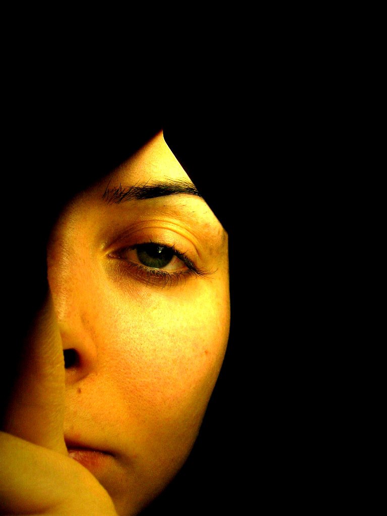 a woman looking away from the camera while holding her hand in front of her face
