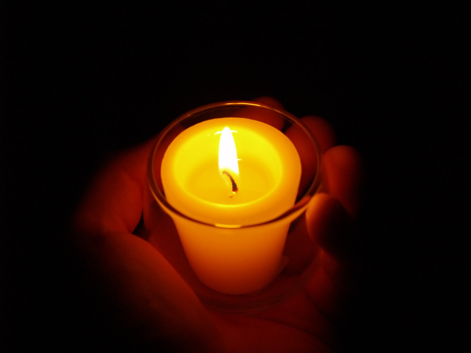 a lit candle that is yellow in the dark