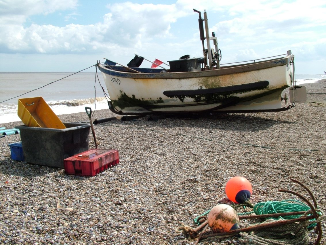 boat and lobster net on pebbly beach area