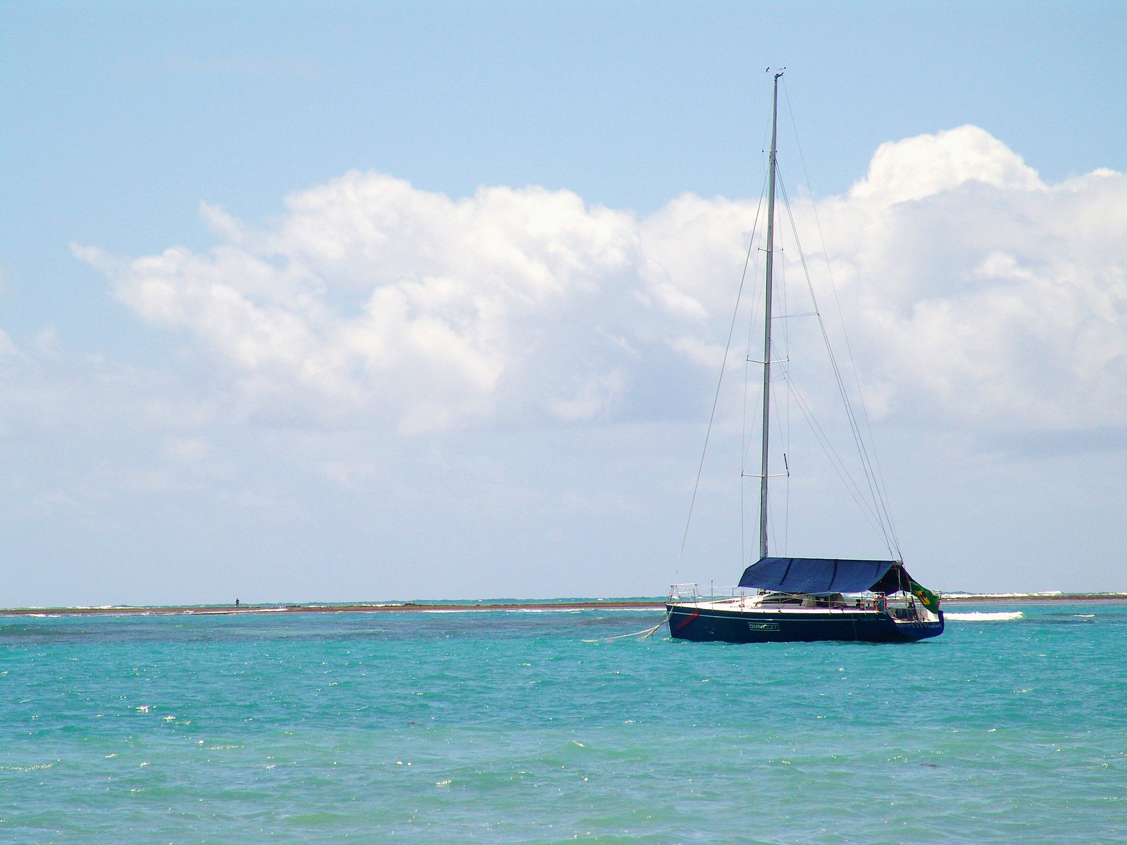 a sailboat sailing in the ocean with a lighthouse on the shore