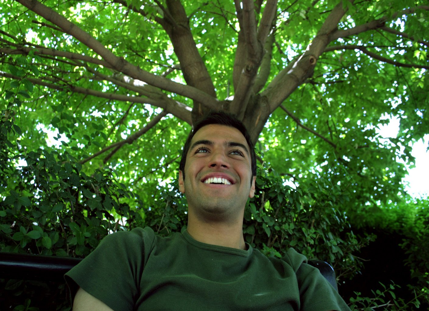 a man is smiling beneath a tree