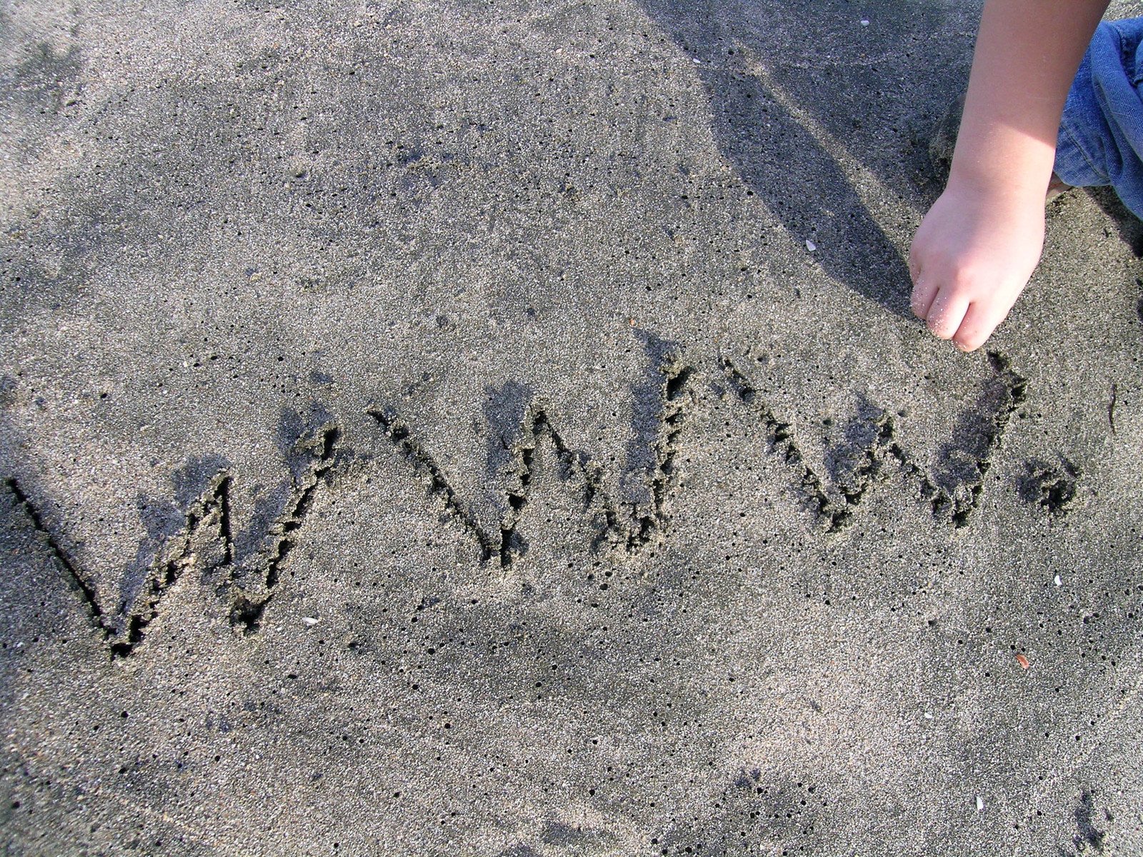 young child writing message on sand on beach